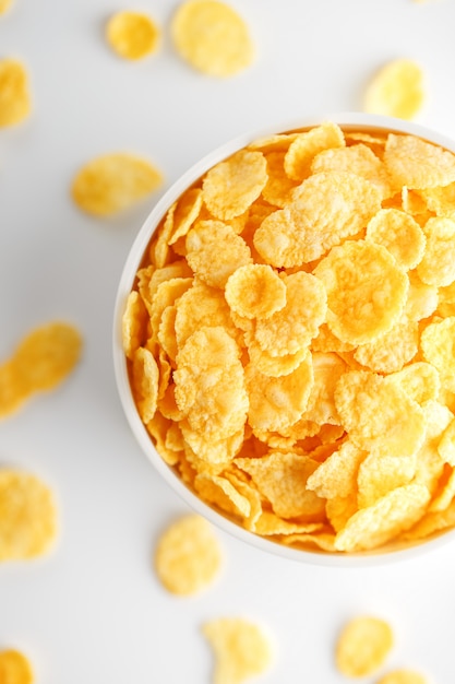 Witte kop met gouden cornflakes die op wit worden geïsoleerd