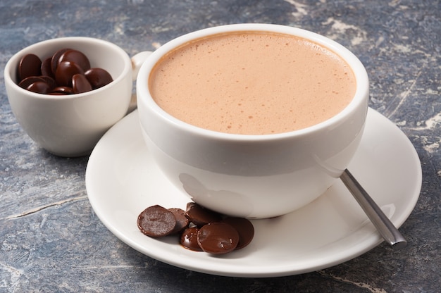 Witte kop warme chocolademelk met melk op een grijze achtergrond