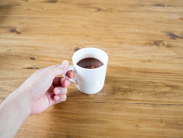 Witte kop warme chocolademelk of koffie geserveerd op houten tafel.