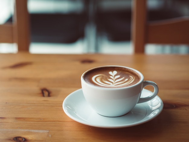 Witte kop warme koffie geserveerd op houten tafel in het café.