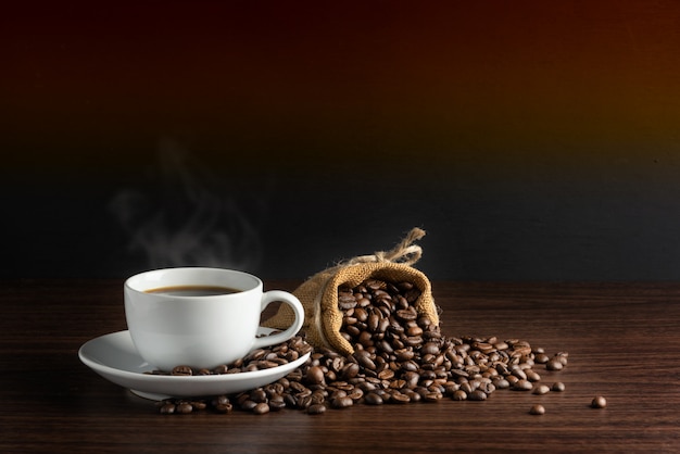 Witte kop warme koffie met rook met koffiebonen en jutehoogtepunt van koffiebonen met touw