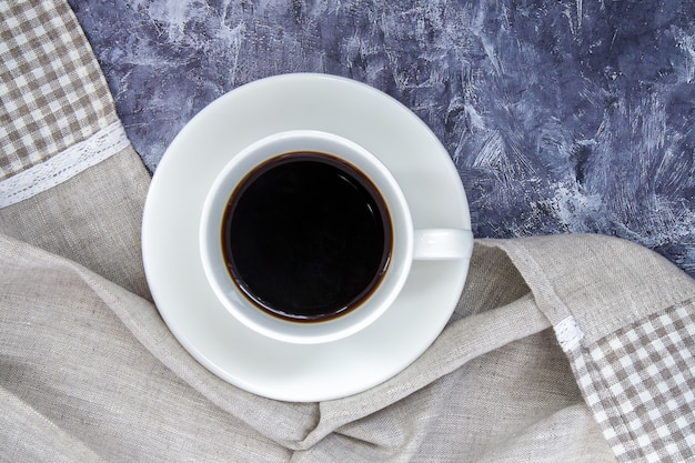 Witte kop zwarte koffie americano en een mooie sjaal gemaakt van stof op een grijze tafel. Mooie kop compositie. Plat lag, bovenaanzicht, kopieer ruimte. Ontspanningsconcept.