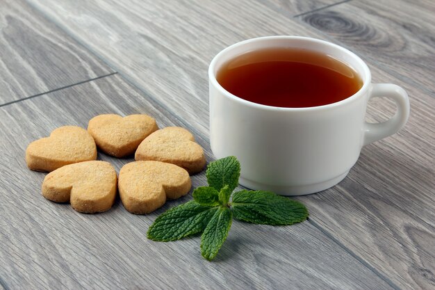 Witte kopje thee met koekjes en munt op tafel