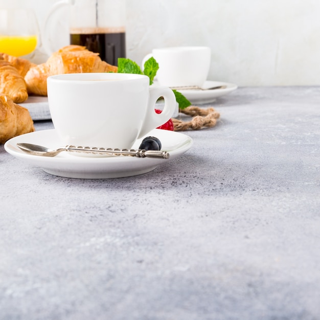 Witte kopjes koffie en croissants