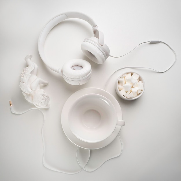 Witte koptelefoon en een witte kop op een witte tafel