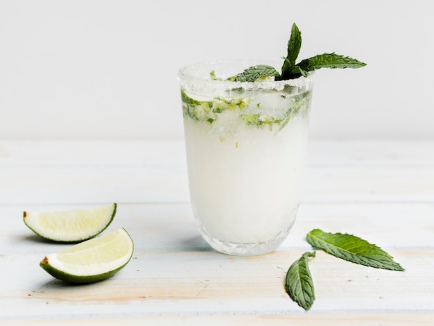 Witte koude cocktail met munt, limoen en ijs in studio