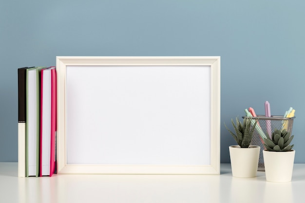 Witte lege houten mock-up frame op wit bureau met papieren notitieboekje boeken bloemen thuis