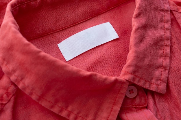 Witte lege kleding label label op rode linnen overhemd stof textuur achtergrond