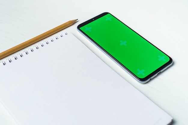 Witte lege notitieblok smartphone groen scherm mockup en potlood plat leggen Tamplate voor ontwerp