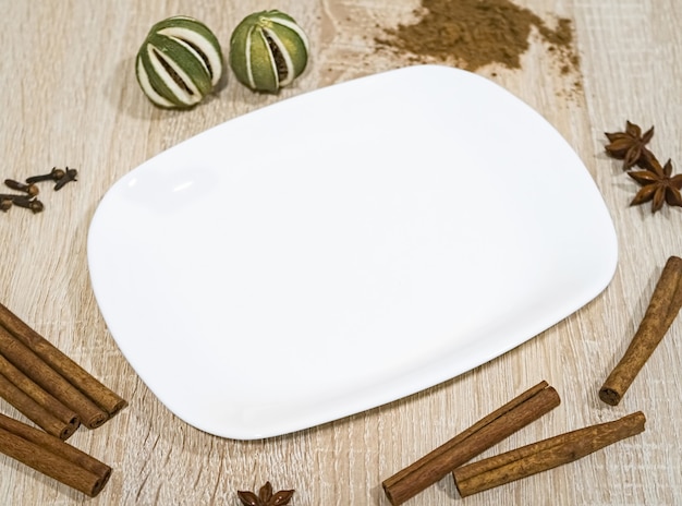 Witte lege plaat op een lichte houten tafel met decoratieve etenswaren eromheen