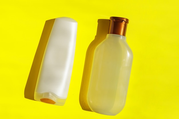 Witte lege plastic cosmetische flessen op gele achtergrond. Plastic afval. Concept van recycling kunststof en ecologie.