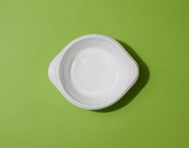 Witte lege plastic soepkom op groene achtergrond bovenaanzicht
