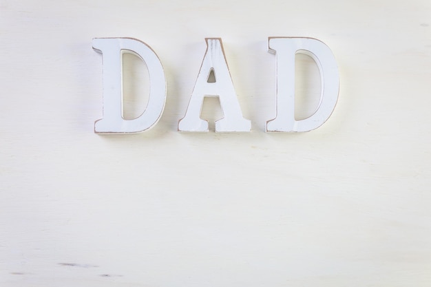 Witte letters DAD op een geschilderde houten ondergrond.