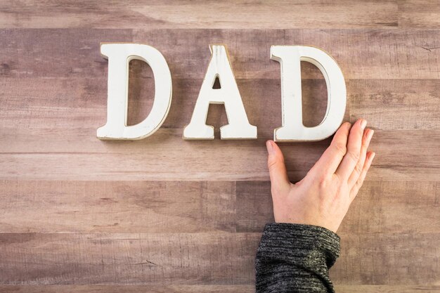 Witte letters DAD op een houten ondergrond.