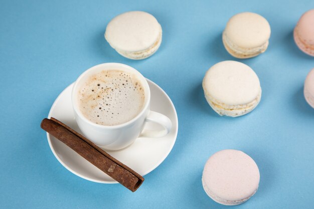 Witte macarons en koffie met kaneel op een blauwe ondergrond