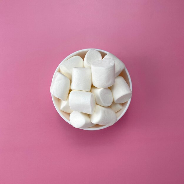 Foto witte marshmallows in een witte schaal op een roze achtergrond