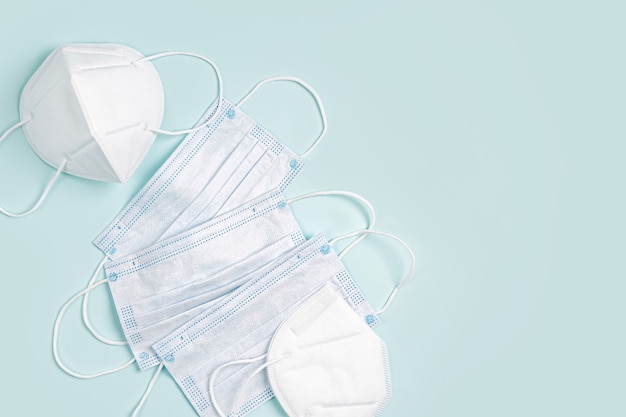 Witte medische maskers en ademhalingstoestellen op blauwe achtergrond. Gezichtsmaskerbescherming KN95 of N95 en chirurgische maskers voor bescherming tegen virus, griep, coronavirus, COVID-19. Medische uitrusting.