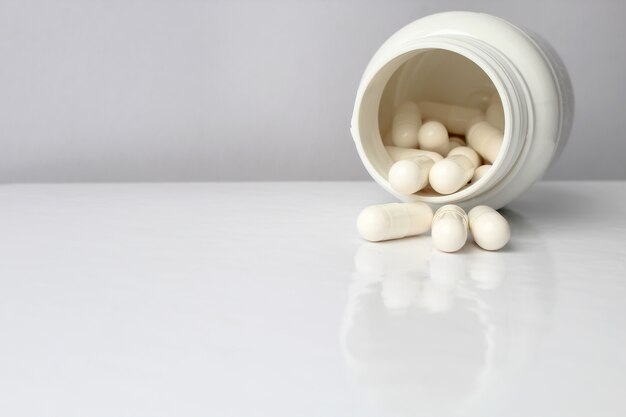 Foto witte medische pillen en tabletten die uit een drugfles morsen.