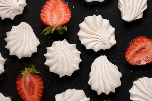 Witte meringue met aardbeien op een zwarte achtergrond