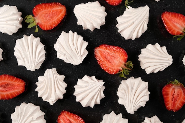 Witte meringue met aardbeien op een zwarte achtergrond