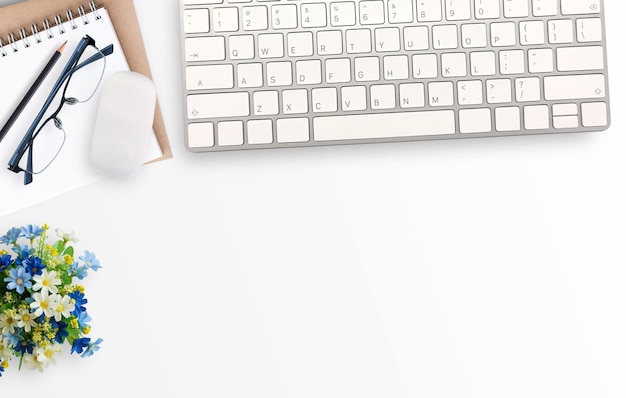 Foto witte minimale kantoor bureau tafel met notebook bril en bloem en mini muis en toetsenbord