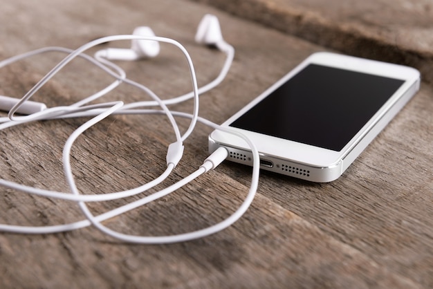 Witte mobiel met koptelefoon op houten tafel