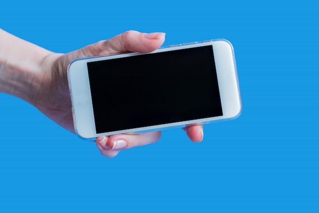 Witte mobiele telefoon in de hand van het linker vrouwtje op blauw met kopie ruimte