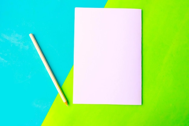 Witte mockup blanco en potlood op geometrische groene en blauwe papieren achtergrond Plat bovenaanzicht minimaal