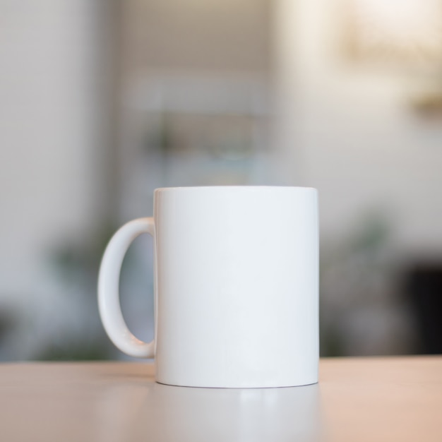 Witte mok op tafel en moderne kamer achtergrond. Lege drankkop voor uw ontwerp.