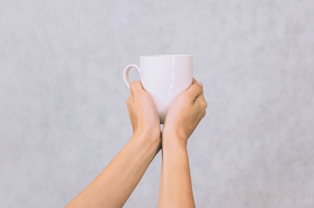 Witte mok voor koffie, thee in de handen van een meisje. op een witte achtergrond.