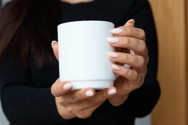 Witte mok voor thee en koffie in de handen van een meisjesclose-up