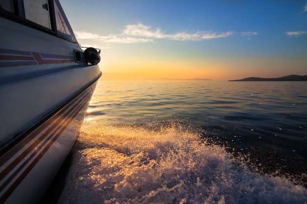 Foto witte motorboot beweegt snel naar zonsondergang