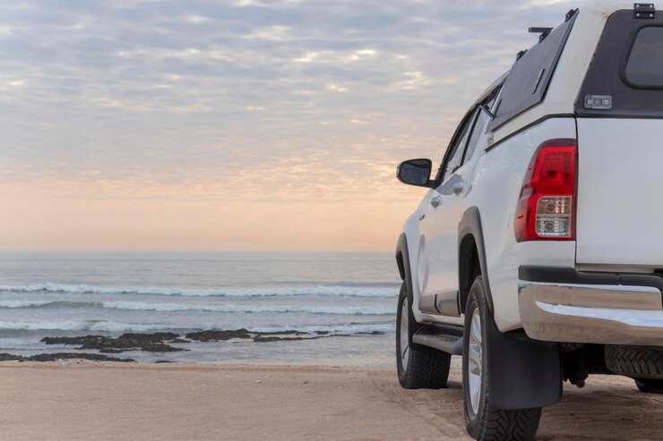 Witte offroad auto staat aan de oevers van de Atlantische Oceaan bij een heldere dramatische zonsondergang