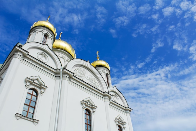 Foto witte orthodoxe kerk met gouden koepels tegen blauwe hemel