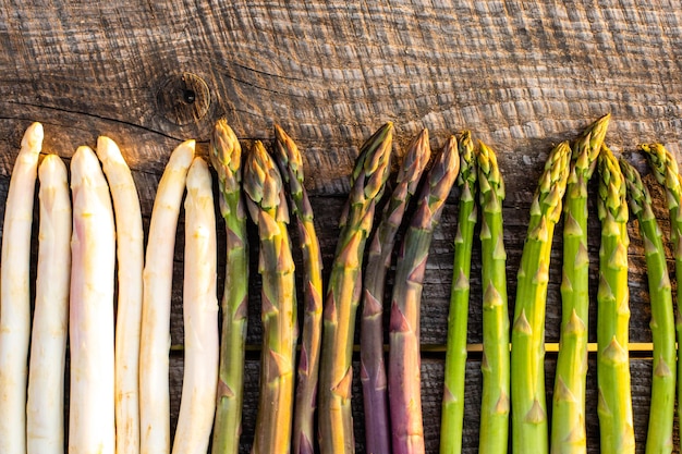 Witte paarse en groene asperges op houten tafel