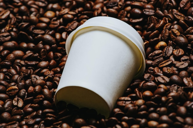 Witte papieren beker op de achtergrond van koffiebonen