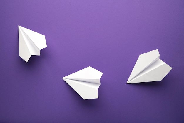 Witte papieren vliegtuigen op een violette achtergrond