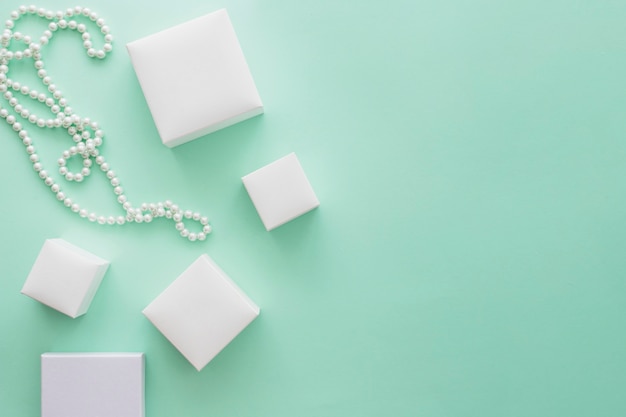 Foto witte parelhalsband met verscheidenheid van witte dozen op bleke groenboekachtergrond