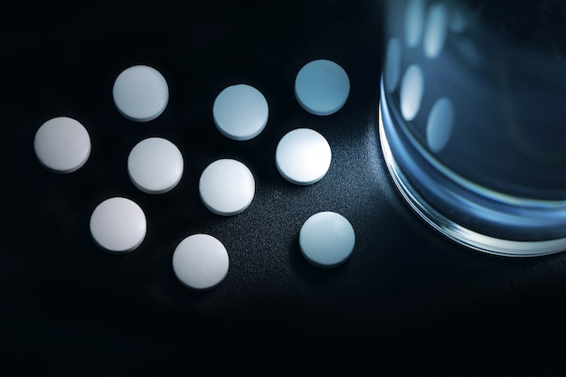 witte pillen geplaatst in de buurt van het glas water op het nachtkastje, slapeloosheid.
