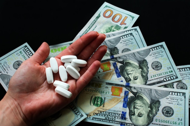 Witte pillen in de hand en dolar op een zwarte achtergrond Veel psychedelische pillen Drugsmisbruik en misdaad