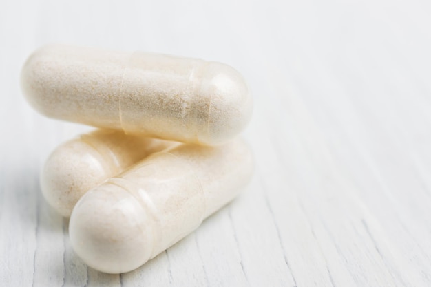 Witte pillen of capsules op witte houten planken, medicamenteuze behandeling, alternatieve geneeskunde, vergrote weergave