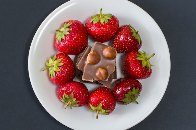 Witte plaat met aardbeien en chocolade geïsoleerde zwarte achtergrond