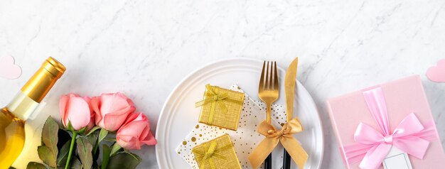 Witte plaat met cadeau en roze roze bloemen voor Valentijnsdag