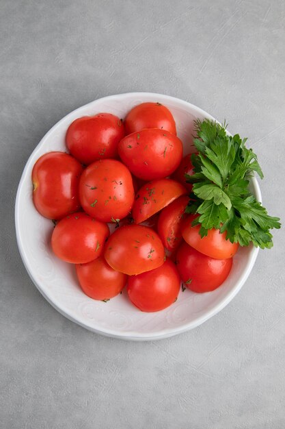 Witte plaat met tomaat en peterselie Kruid met zongedroogde tomaten en grijze achtergrond