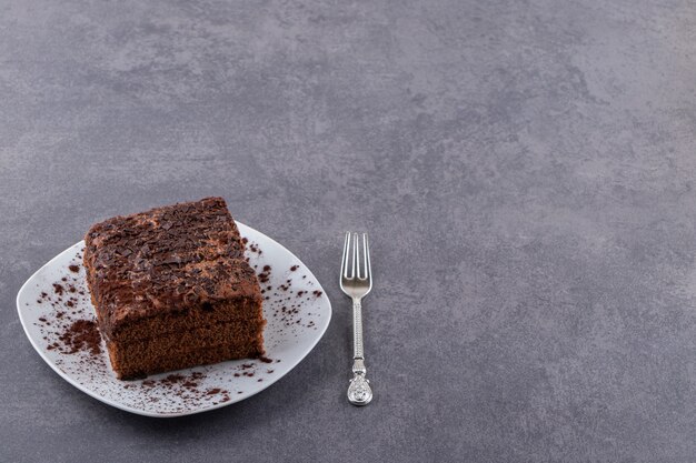 Witte plaat van zoete gesneden koek op stenen tafel.