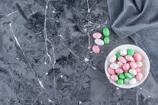 Witte plaat vol kleurrijke bonbons op marmeren tafel.