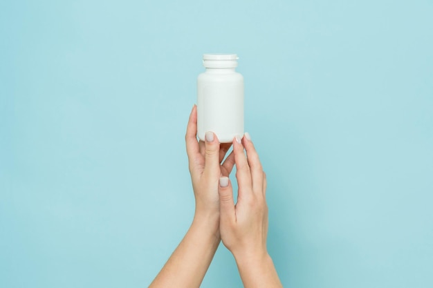 Witte plastic buis in vrouwelijke hand Fles voor pil capsule of supplement Product branding mockup