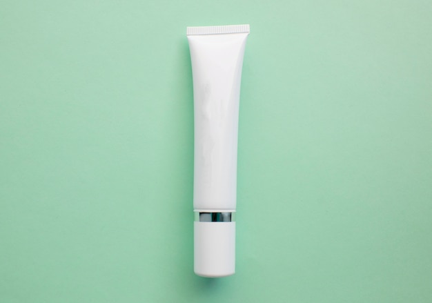 Witte plastic crème tube met ruimte voor tekst op een lichtgroene achtergrond, minimalisme