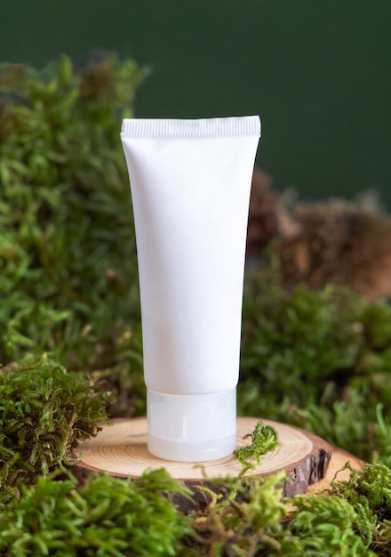 Witte plastic crème tube op houten stuk tussen groen mos close-up natuurlijke cosmetische mockup