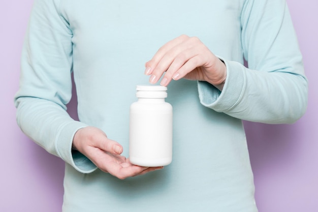 Witte plastic fles in vrouwelijke hand Verpakking voor pillen, capsules of supplementen
